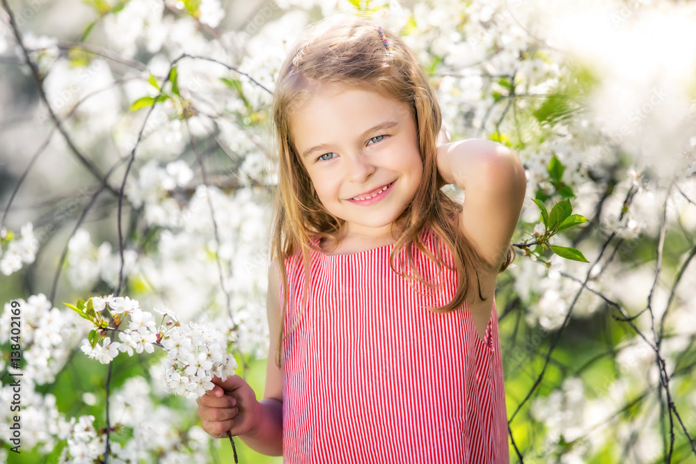 Happy little girl playing in spring cherry garden Happy little girl playing in spring cherry garden