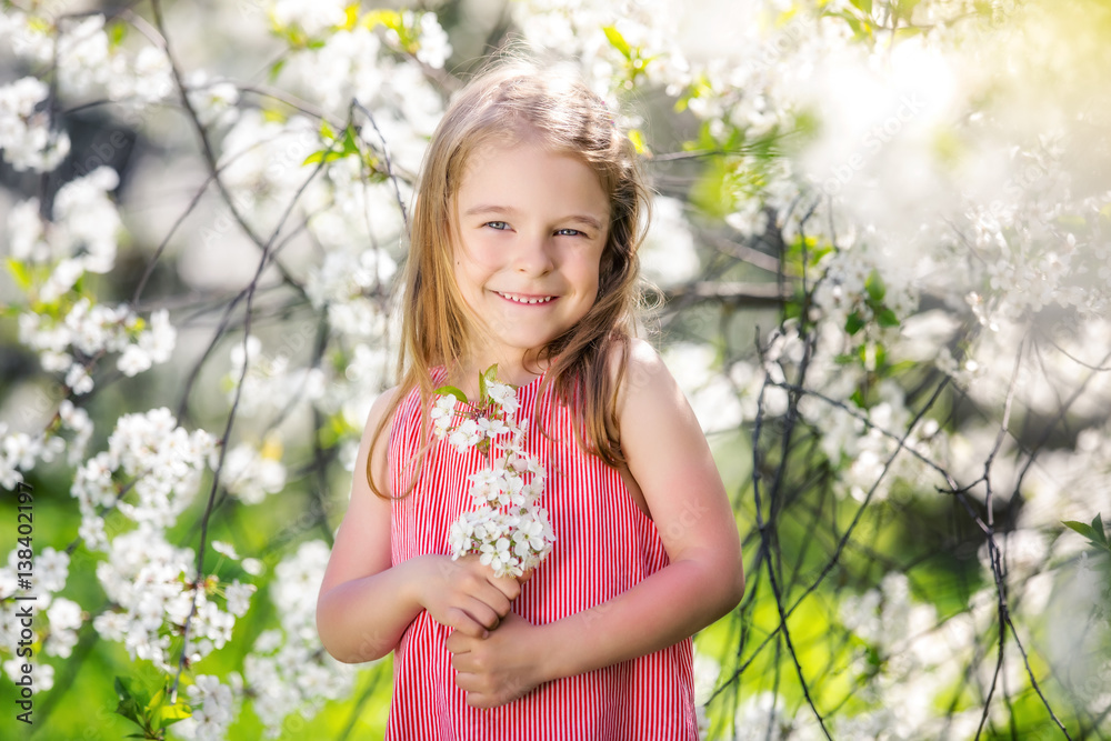 Fototapeta premium Happy little girl playing in spring cherry garden