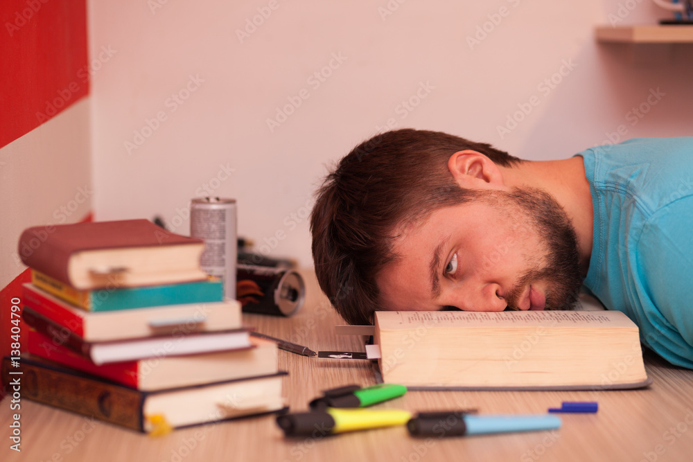 Comatose student with his head lying in the middle of a book while studying Comatose student with his head lying in the middle of a book while studying