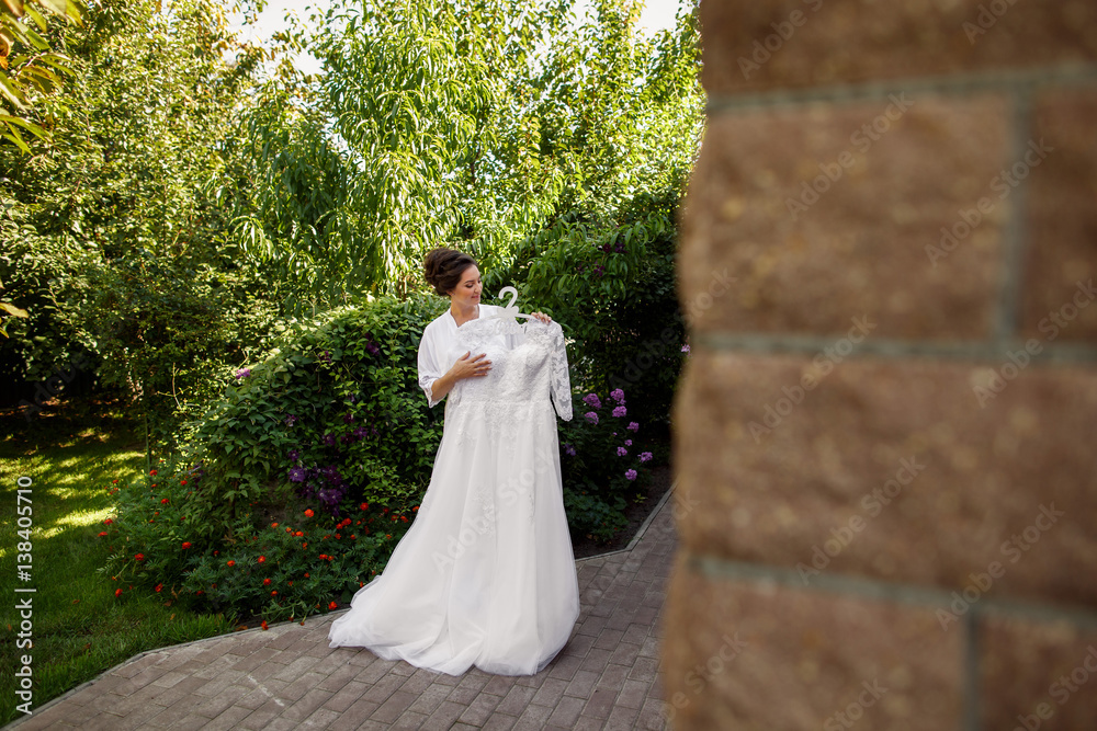 Bride holding white wedding dress in garden in wedding morning. Russian translation of the inscription 