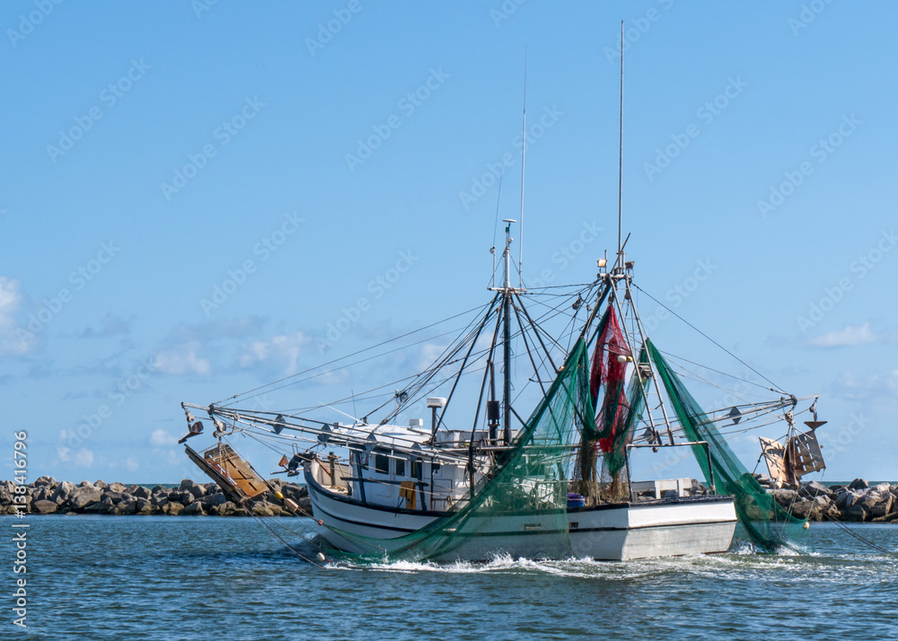 Shrimp fishing boat trawler sailing on water out to the Gulf of Mexico in Florida