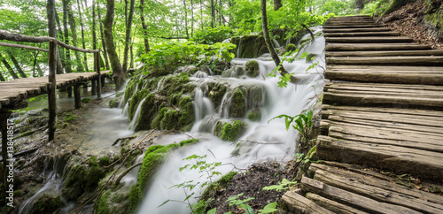 Slika na platnu A wooden pathway meanders over waterfalls and through the forest at Plitvice Lakes National Park in Croatia
