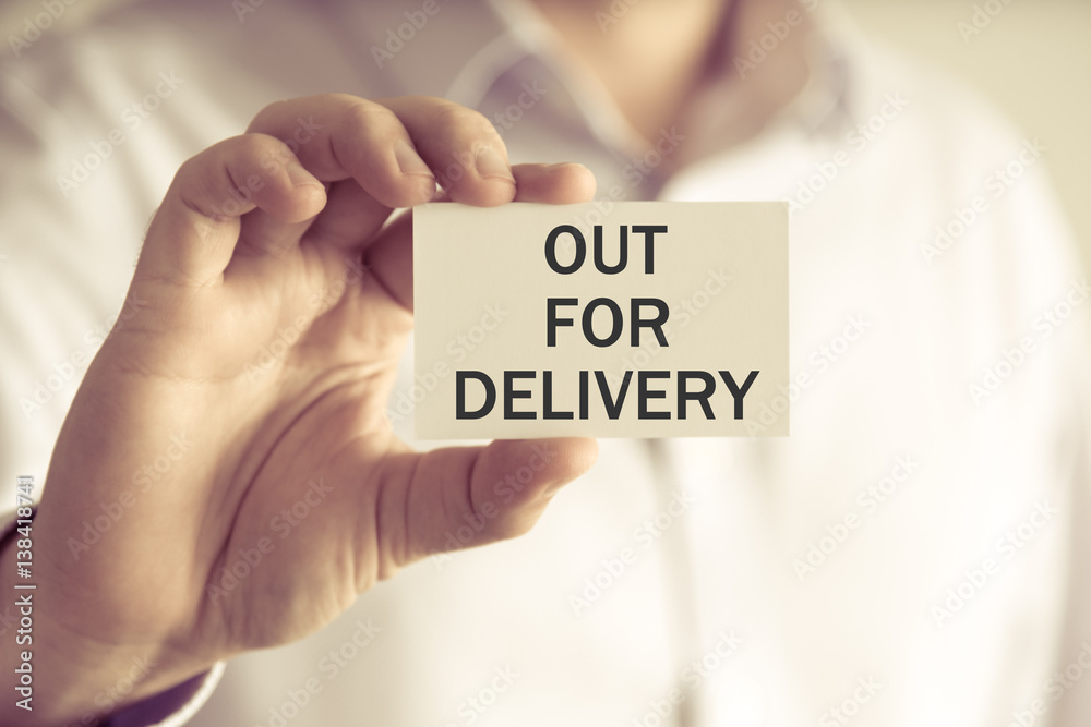 Businessman holding OUT FOR DELIVERY message card