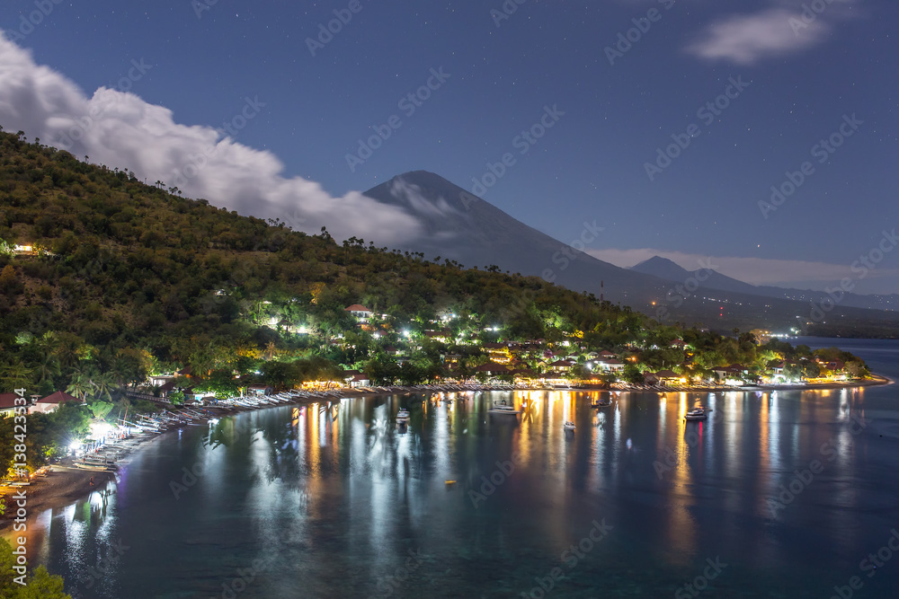 Jemeluk Beach and beautiful Agung volcano with a stars sky at night, Amed village, East of Bali, Indonesia.