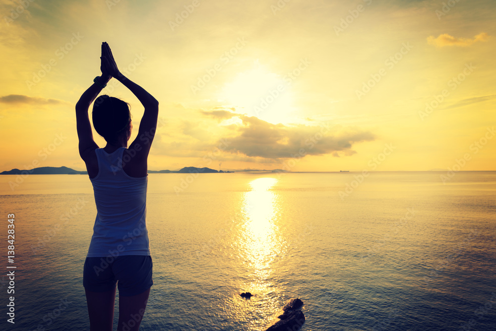 young fitness woman practicing yoga at sunrise seaside