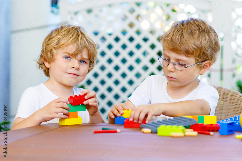 Two little kid boys playing with plastic blocks together Two little kid boys playing with plastic blocks together