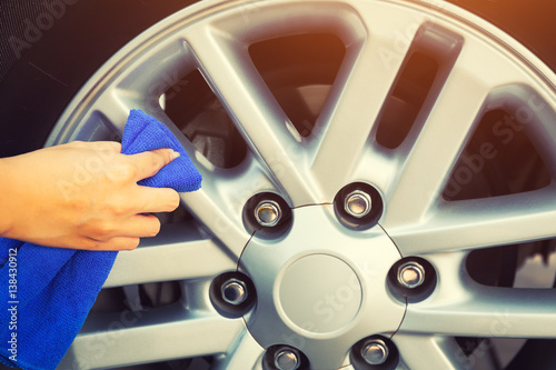 Women's hand wiping on alloy Wheels.