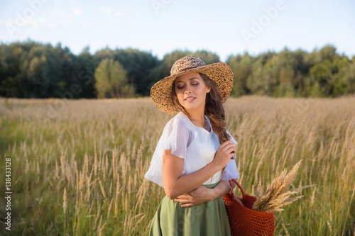 Girl with circlet of flowers walking in golden dried grass field