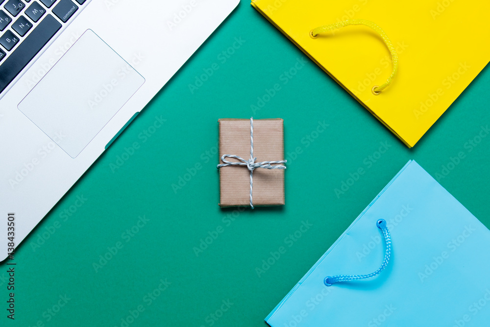 beautiful shopping bags, cute gift and modern silver laptop on the wonderful blue background