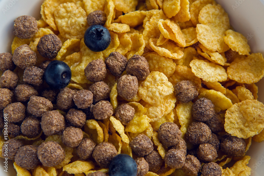granola with blueberries in white bowl on wooden white background