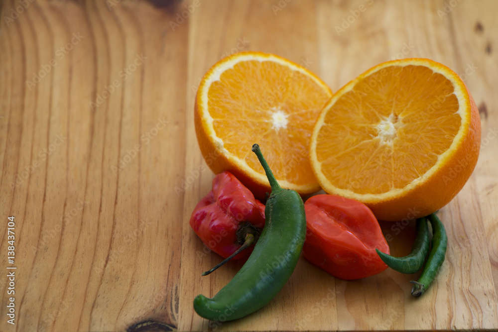 red & green chilli with orange sliced open on a wooden cutting board red & green chilli with orange sliced open on a wooden cutting board