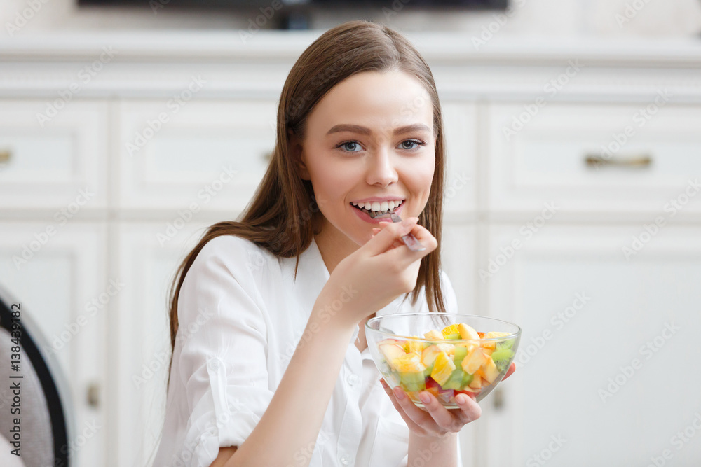 Young woman eating healthy fruit breakfast in bowl at home Young woman eating healthy fruit breakfast in bowl at home