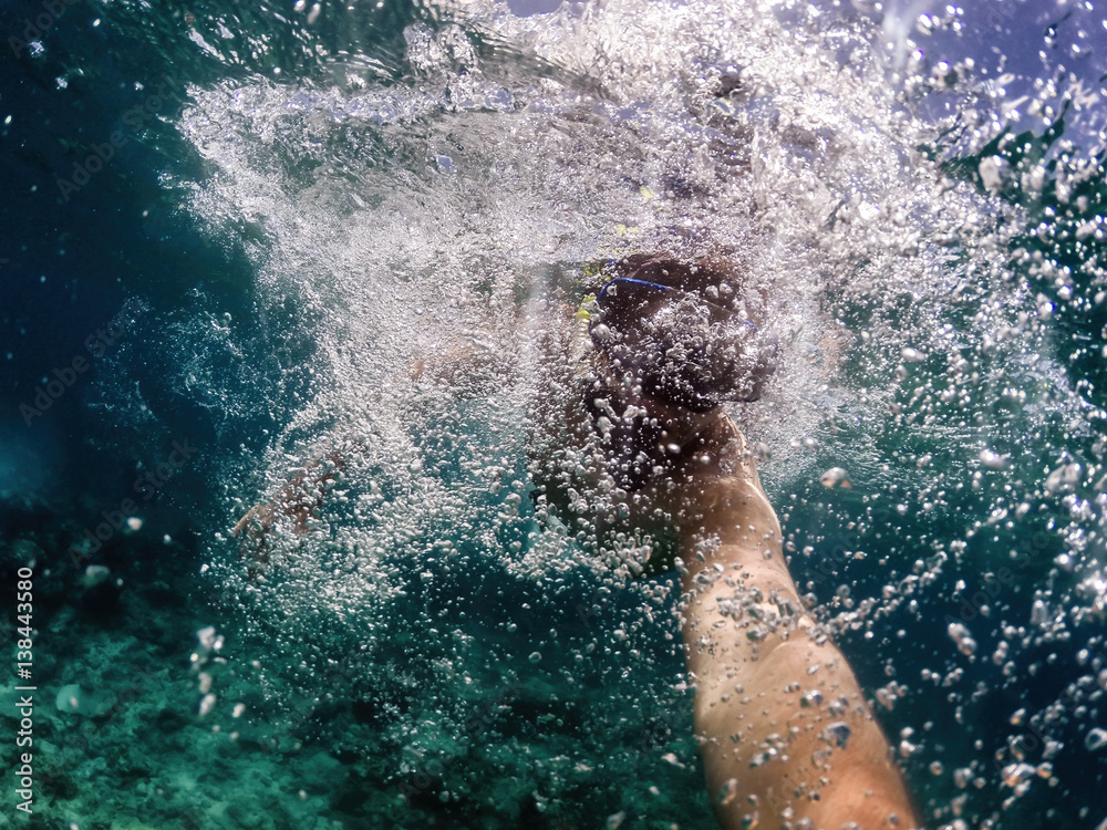 Young diver in action takes selfie, swimming under water enjoying summertime. Holidays and fun.