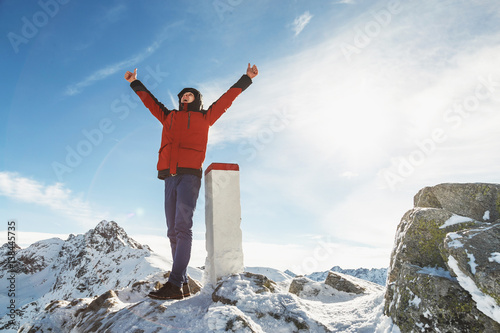 Man on the mountain top raised his hands shouts with joy of his achievements.