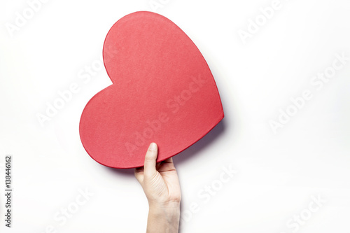 Woman hand hold a red heart gift box isolated white.