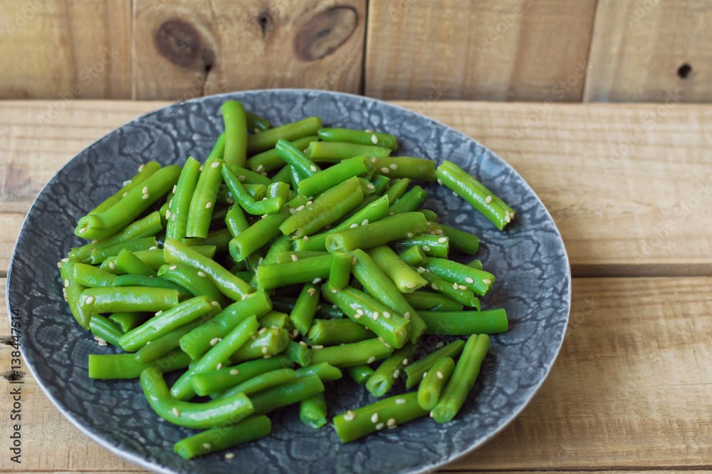 Plate with cooked green beans with sesame seeds on wooden background Plate with cooked green beans with sesame seeds on wooden background