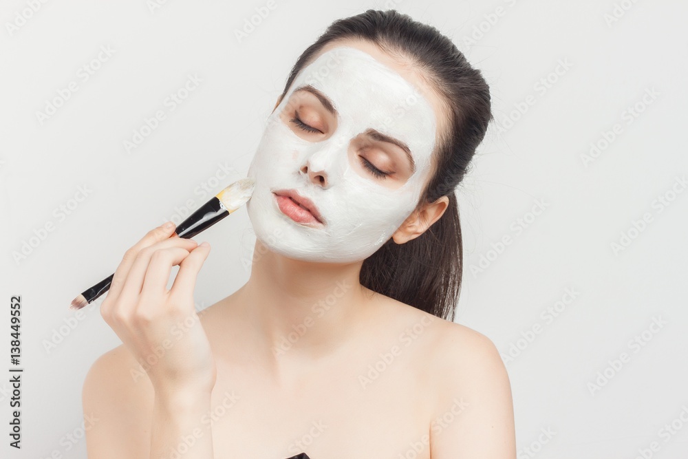 woman with make-up brush applies white cream on face woman with make-up brush applies white cream on face