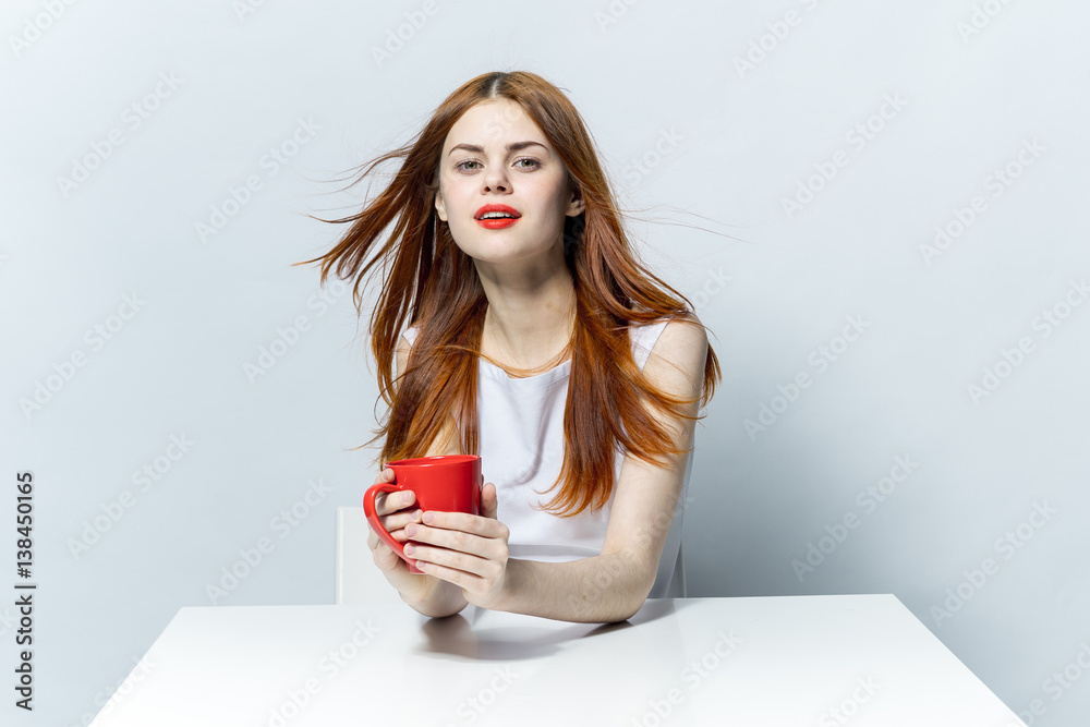 woman with red mug sits at table woman with red mug sits at table