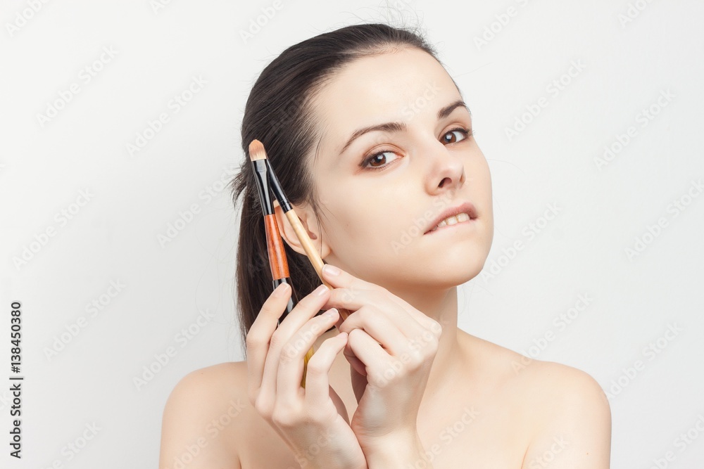 makeup brush near the face of a woman