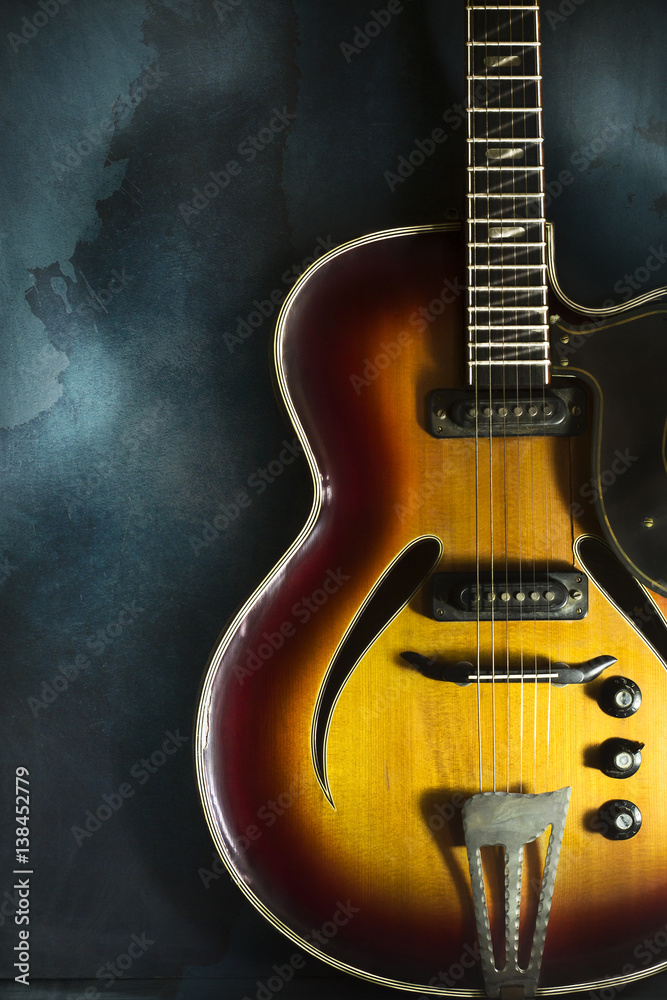 Fototapeta premium Close-up of old electric jazz guitar on a dark blue background