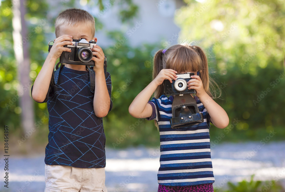Little boy and a little girl wit two vintage cameras standing together ...