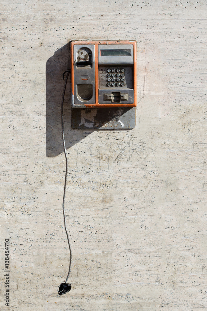 Damaged public phone with hanging handset