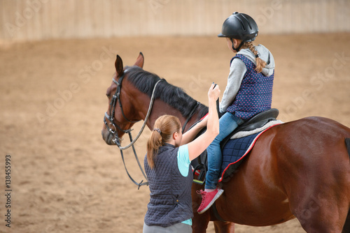 Girl in helmet Learning Horseback Riding. Instructor teaches teen Equestrian.