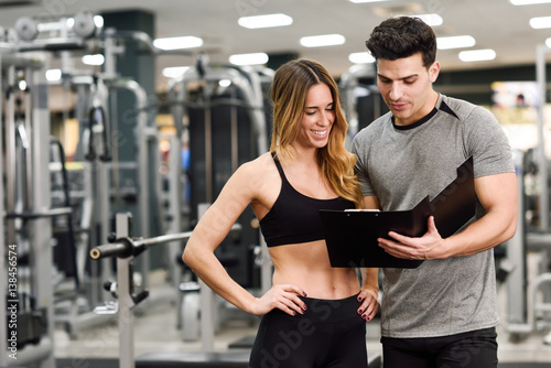 Personal trainer and client looking at her progress at the gym