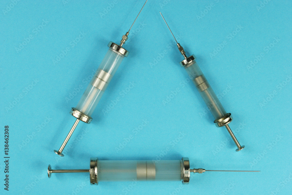 old injecting syringe on blue background old injecting syringe on blue background