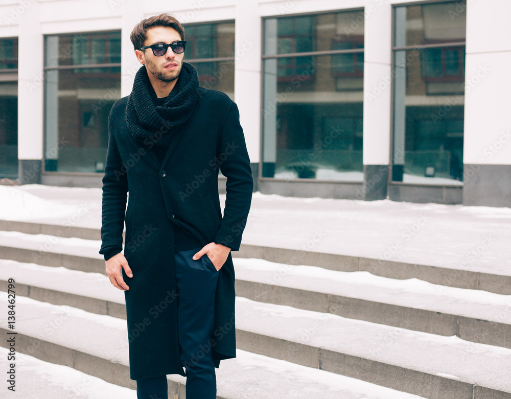 Elegant young handsome business man wearing suit and black coat posing