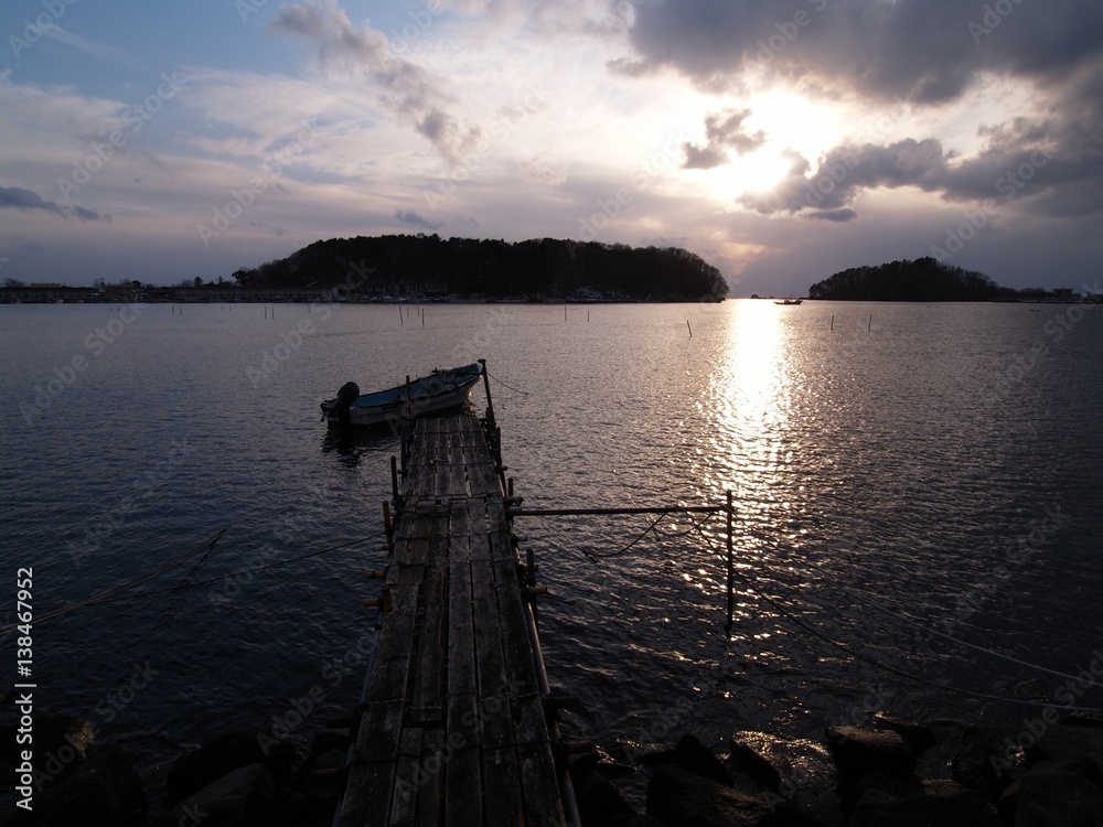 島のシルエットと夕日　古い桟橋と漁船