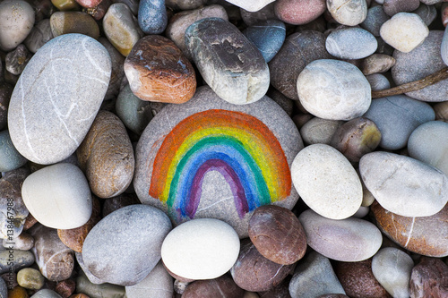 Rainbow painted on pebble with stones background photo