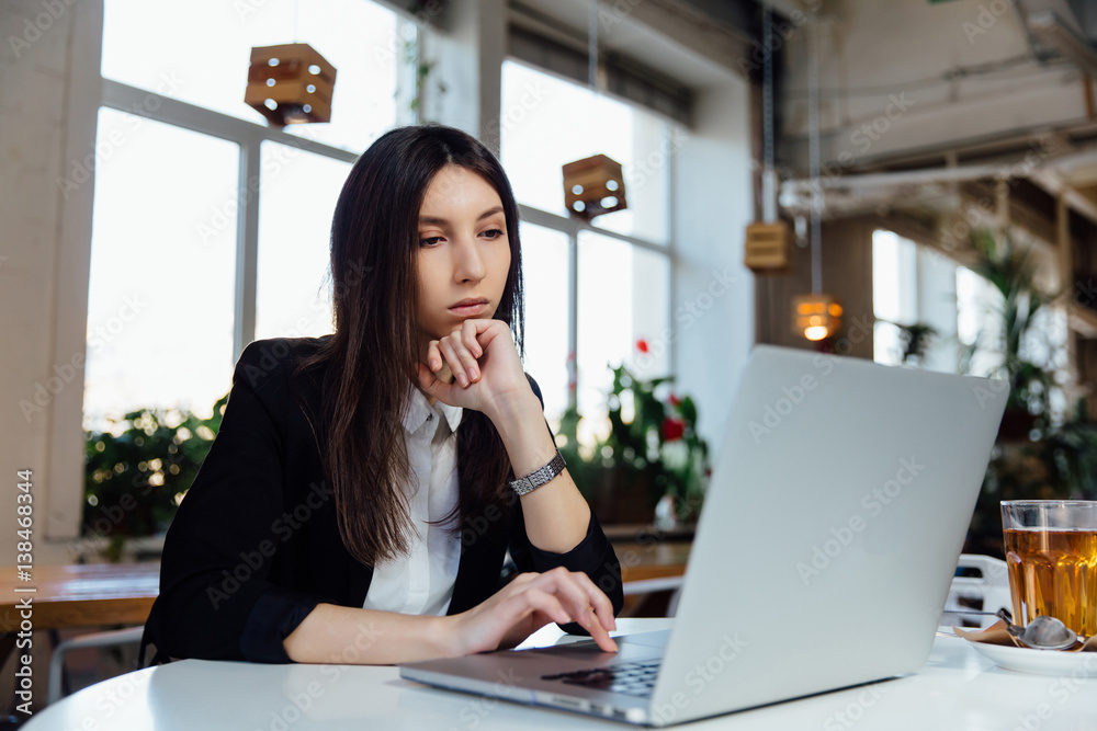Young business woman sitting at table in cafe, . Working with the notebook and glass of tea. Young business woman sitting at table in cafe, . Working with the notebook and glass of tea.