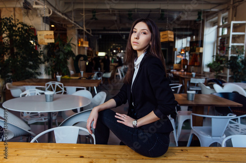 Portrait of a young cute brunette girl business in the interior hipster cafes. Long hair.