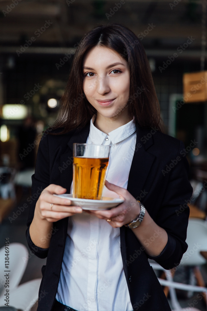young cute brunette girl business in the interior hipster cafes holding a glass of tea. young cute brunette girl business in the interior hipster cafes holding a glass of tea.