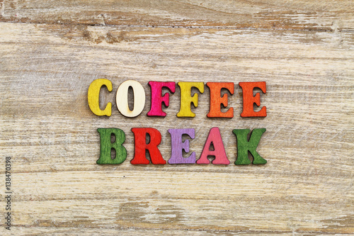 Coffee break written with colorful letters on rustic wooden surface
