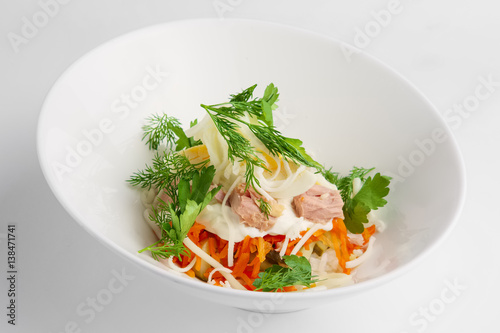 Plate with tuna salad with eggs, carrot, onion and mayonnaise on white background