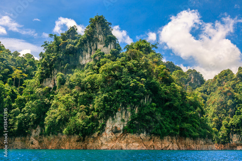 Mountain island full of green tree with deep blue water and clear sky. © Teeranon