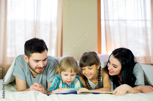 Family reading a book in bed
