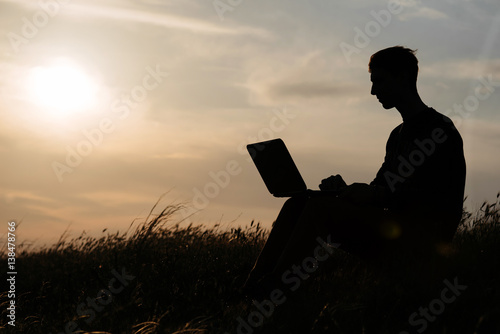 teamwork of two man at the top of mountain. silhouette at sunset