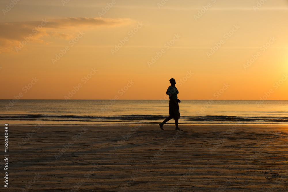 silhouette of a man jogging on the beach at sunset, healthy lifestyle