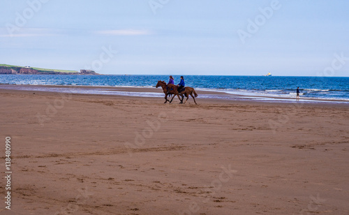 Horses being ridden on beach at Lunan Bay, Montrose, Scotland, UK