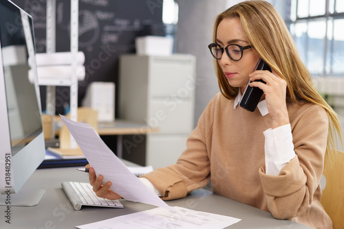 frau im büro mit telefon und unterlagen