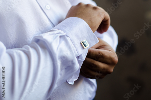 The handsome groom wears a wedding cufflinks