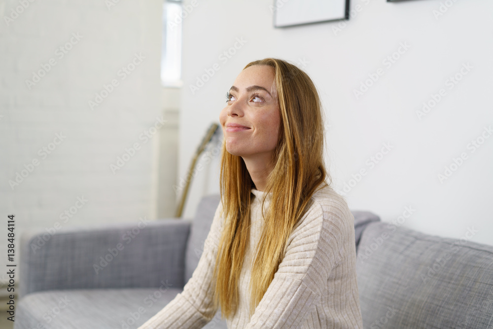 Naklejka premium frau sitzt entspannt auf dem sofa und schaut lächelnd nach oben
