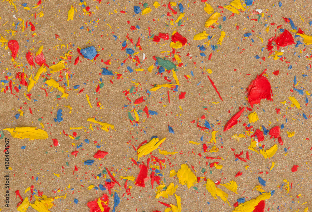 Colored particles of dry oil paint on golden paper background