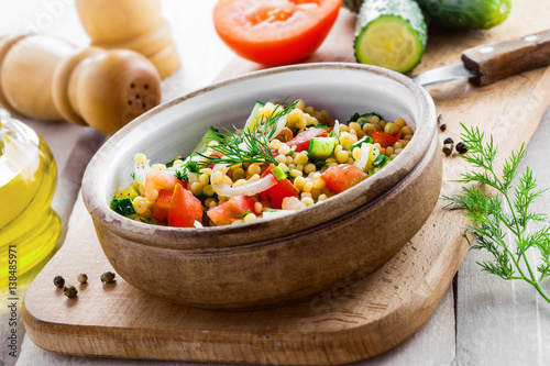 Delicious Israeli couscous Ptitim with vegetables on a white wooden table. Cooking of healthy vegetarian food for the meal. Traditional Moroccan cuisine.