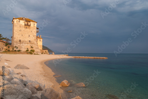Beach with rocks, ancient stone tower and clear water at sunset