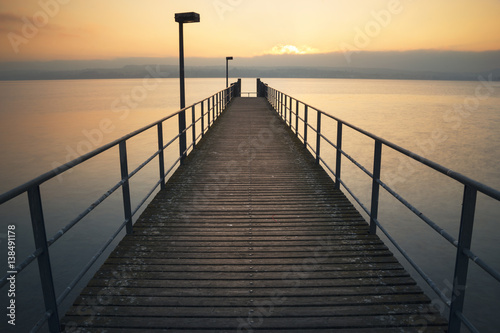 Ein symmetrischer ruhiger Holzsteg am Bodensee bei Sonnenuntergang © manushot