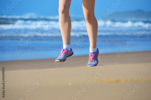 Fitness and running on beach, woman runner legs in shoes on sand near sea, healthy lifestyle and sport concept 